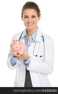 Smiling medical doctor woman holding piggy bank