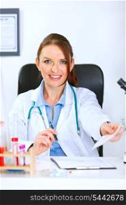 Smiling medical doctor woman sitting at table and giving medical prescription&#xA;