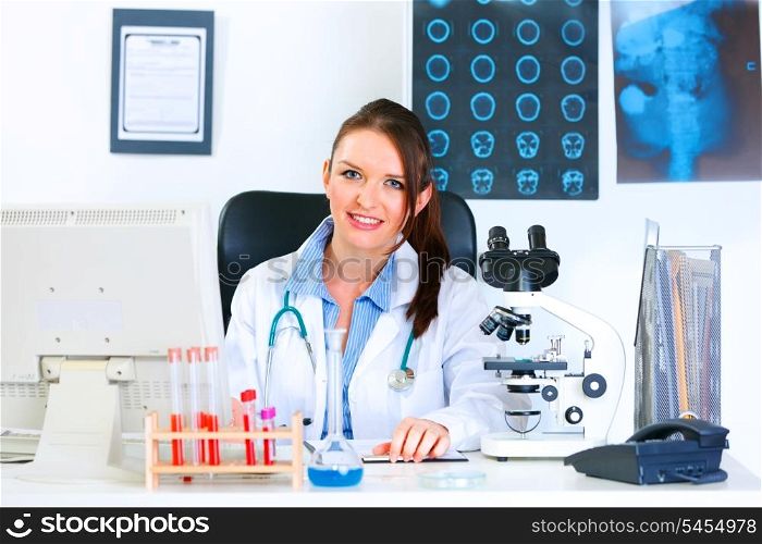 Smiling medical doctor woman sitting at table in office&#xA;