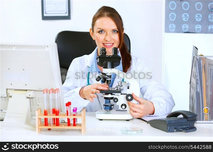 Smiling medical doctor woman using microscope in laboratory&#xA;