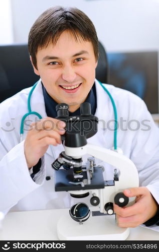 Smiling medical doctor working with microscope in laboratory&#xA;