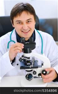 Smiling medical doctor working with microscope in laboratory&#xA;