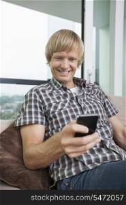 Smiling mid-adult man text messaging on sofa at home