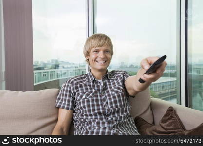 Smiling mid-adult man watching television on sofa at home