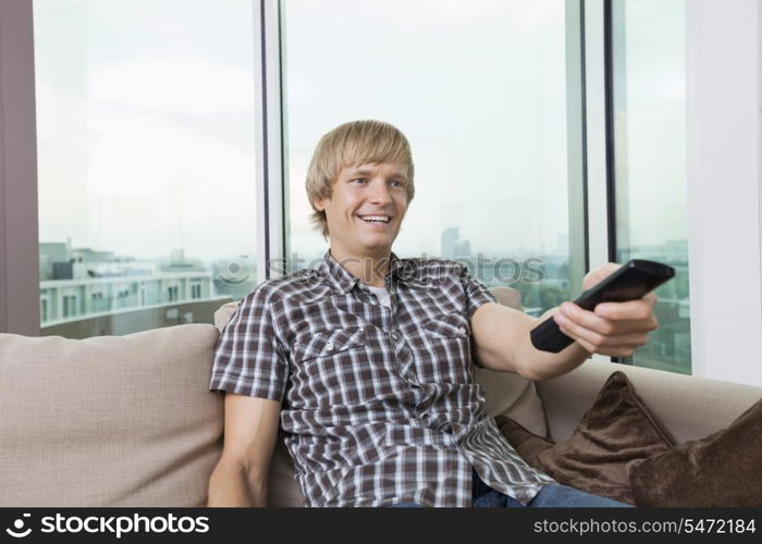 Smiling mid-adult man watching television on sofa at home