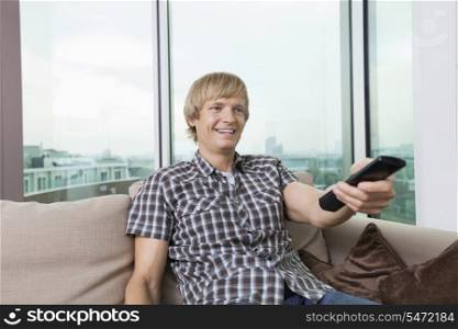 Smiling mid-adult man watching television on sofa at home