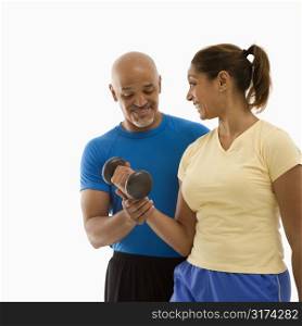 Smiling mid adult multiethnic man assisting mid adult multiethnic woman with dumbbells.