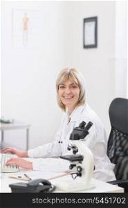 Smiling middle age doctor woman working at laboratory