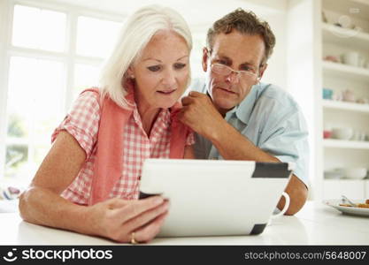 Smiling Middle Aged Couple Looking At Digital Tablet