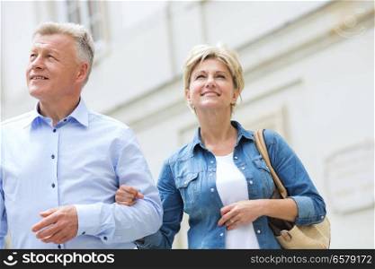 Smiling middle-aged couple standing with arm in arm outdoors