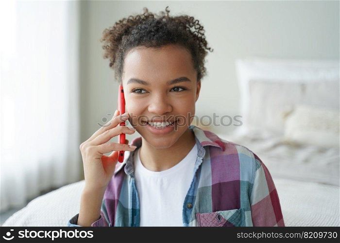 Smiling mixed race teen girl answers phone call, chatting by mobile at home, friendly biracial young lady holding smartphone enjoying conversation, pleasant talk with friend in bedroom at home.. Smiling mixed race teen girl answers phone call, enjoying talk with friend in bedroom at home