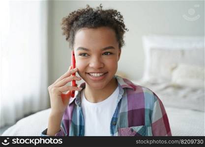 Smiling mixed race teen girl answers phone call, chatting by mobile at home, friendly biracial young lady holding smartphone enjoying conversation, pleasant talk with friend in bedroom at home.. Smiling mixed race teen girl answers phone call, enjoying talk with friend in bedroom at home