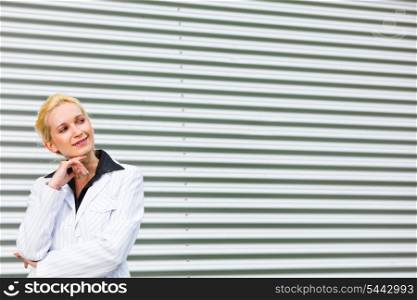 Smiling modern business woman standing at office building and looking at copyspace &#xA;