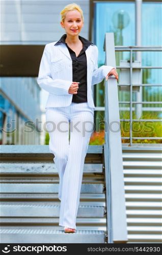 Smiling modern business woman walking down stairs&#xA;