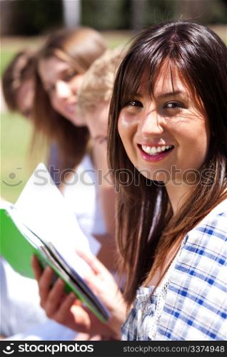 Smiling modern female student in focus with friends at the back