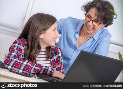 smiling mom and daughter using a laptop at home