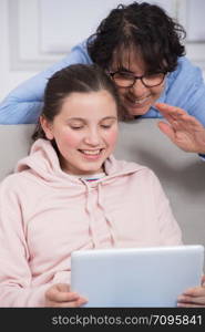 smiling mom and daughter using a tablet computer at home