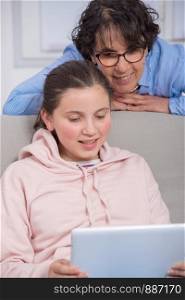 smiling mom and daughter using a tablet computer at home