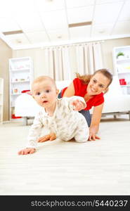 Smiling mommy playing with creeping on floor baby&#xA;