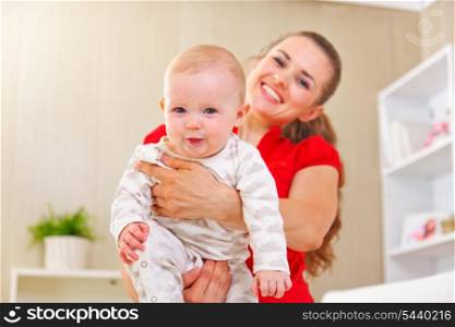 Smiling mother and adorable baby playing at home