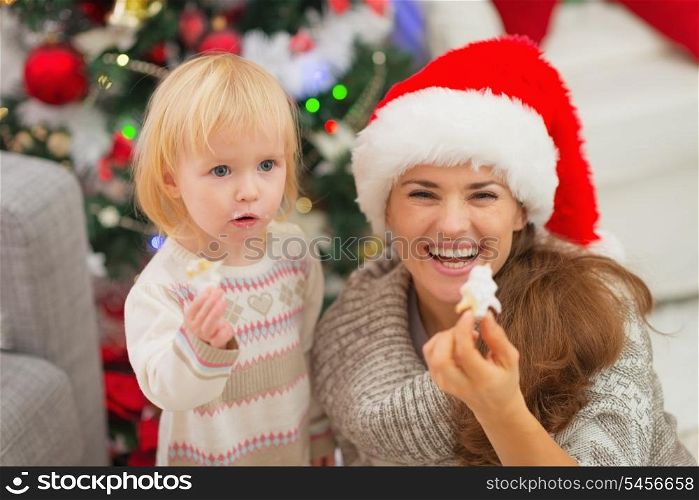 Smiling mother and baby eating Christmas cookies