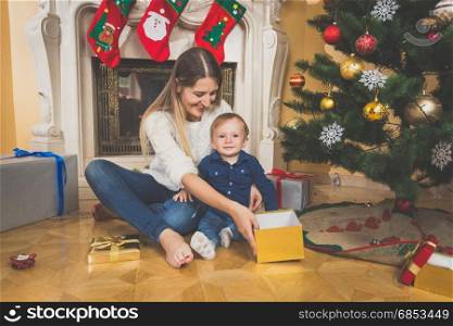 Smiling mother and baby on floor looking at Christmas gifts