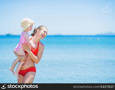 Smiling mother and baby on sea background looking on copy space