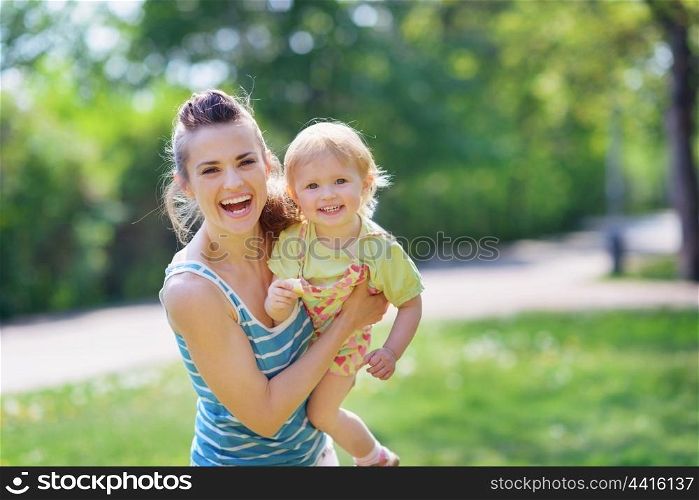 Smiling mother and baby playing in park