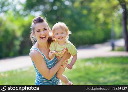 Smiling mother and baby playing in park