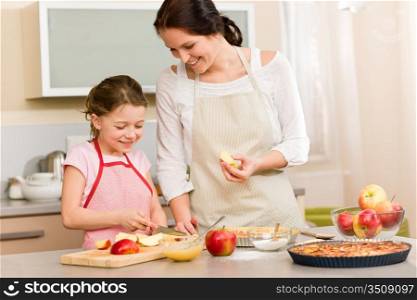 Smiling mother and daughter cutting apples for baking a pie