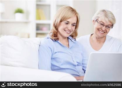 Smiling mother and daughter looking at laptop
