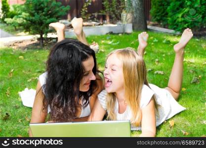 Smiling mother and daughter rest upon herb in summer