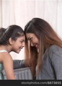 Smiling mother and daughter touching foreheads