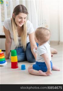 Smiling mother assembling toy pyramid with her baby boy