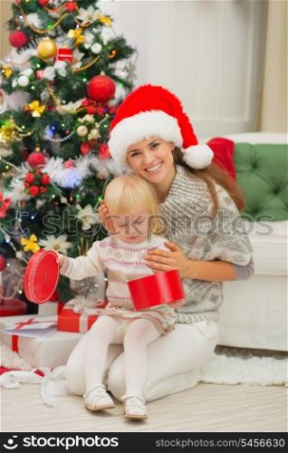 Smiling mother holding baby opening Christmas present box