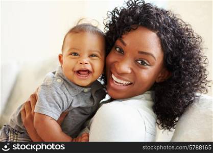 Smiling Mother Playing With Baby Son At Home