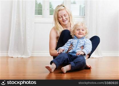 Smiling mother with cute little boy child sitting in house