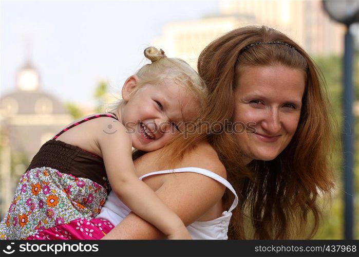 smiling mother with daughter at the cityscape outdoor