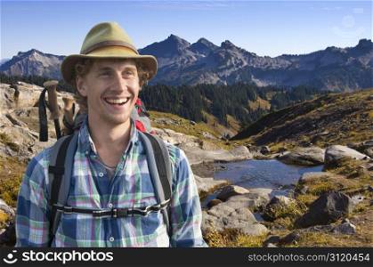 Smiling mountain guide with a backpack and walking stick on his back on a sunny afternoon in the middle of nowhere