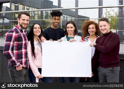smiling multiethnic students holding blank white poster standing front glass building