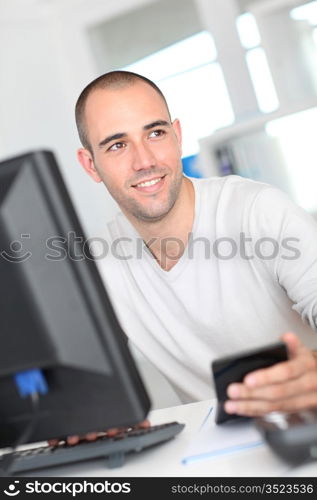 Smiling office worker sitting in front of desktop computer