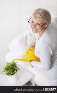 Smiling older woman watering houseplant