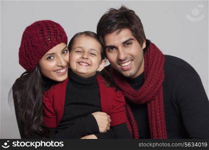 Smiling parents with their daughter over grey background