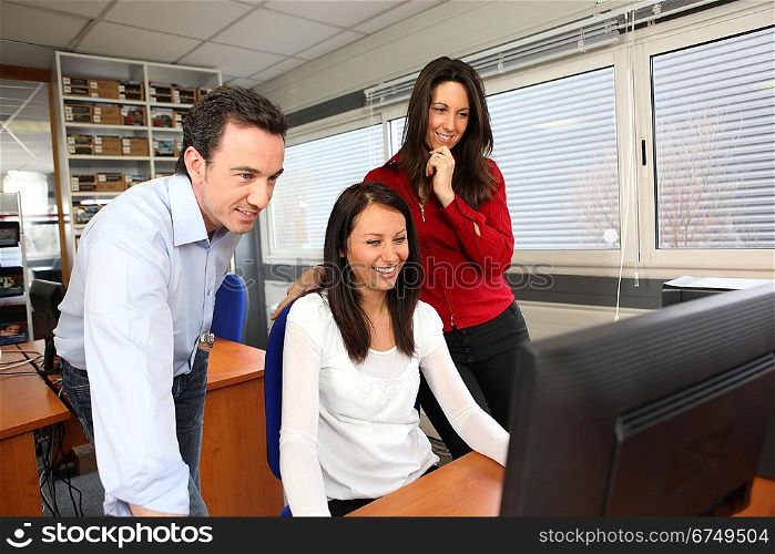 Smiling people using a computer in an office