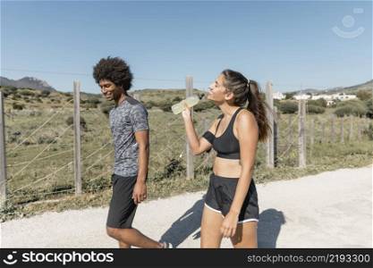 smiling people walking while woman drinking water