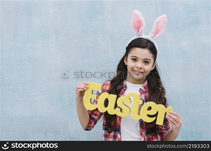 smiling portrait girl holding yellow easter word looking camera