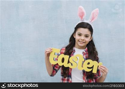 smiling portrait girl holding yellow easter word looking camera