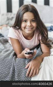 smiling portrait girl lying bed using remote control