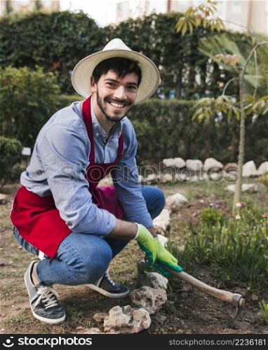smiling portrait male gardener digging soil with hoe vegetable garden