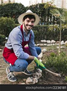 smiling portrait male gardener digging soil with hoe vegetable garden